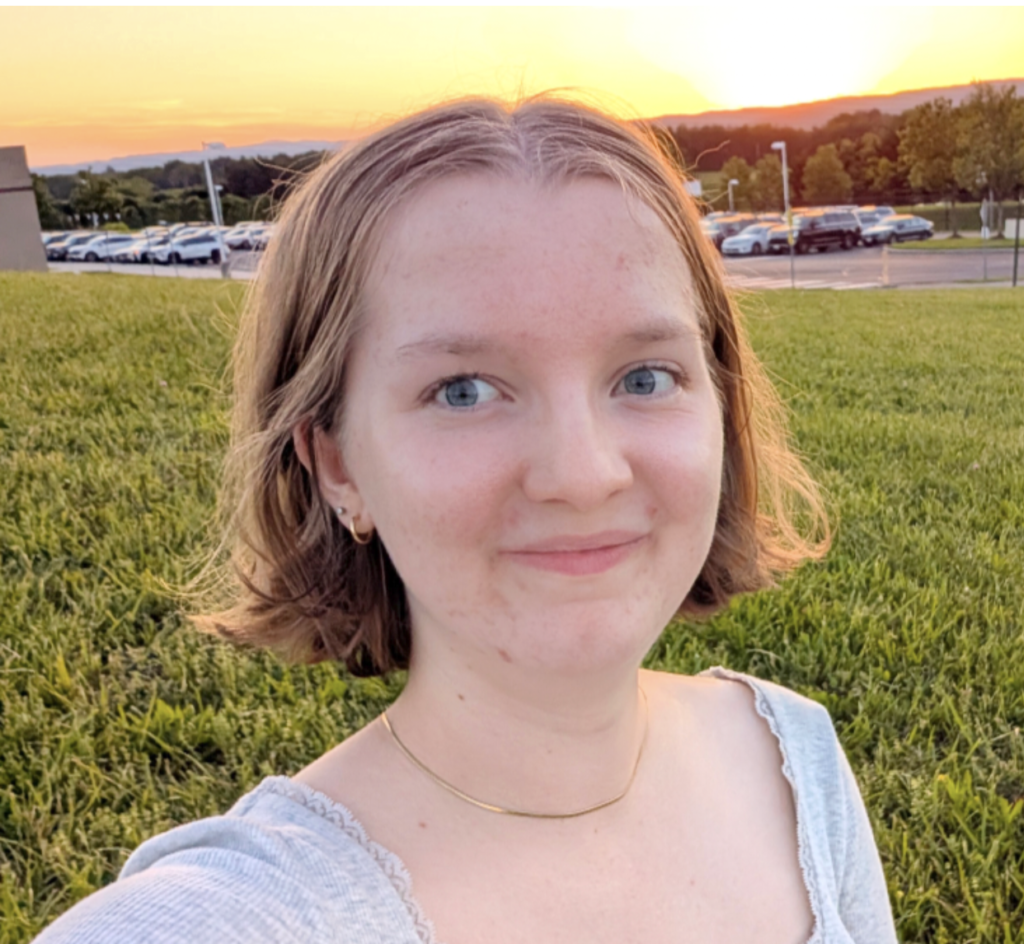 Genevieve Cruikshank snaps a selfie on the lawn in front of a sunset, while wearing gold jewelry.